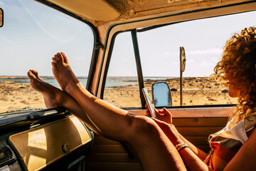Interior of classic van camper with beautiful legs of woman stretched and relaxed. Travel people lifestyle concept. Summer holiday vacation and vanlife. Dreamcatcher and beach view holiday vacation - obrazy, fototapety, plakaty