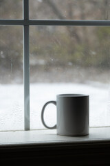 cup in window with snow in the background