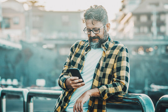 Modern young mature man using phone device outdoor with free internet wifi connection or dat roaming technology. Tourist in the city destination use cellular to plan visits and booking hotel room