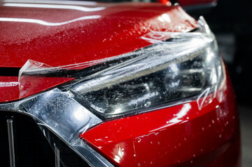 Close-up of a red car headlight with vinyl wrap.  © Михаил Решетников