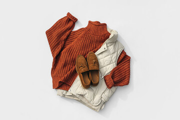 Fashion autumnal outfit. Knitted brown sweater with down vest jackets and loafers. Women's warm...