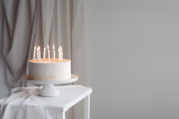 White and gold birthday cake with candles on the white table, minimalistic style. Generative AI