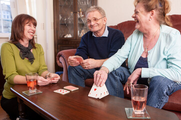 Help the Aged: FAmily Games. A mature woman visiting her aging parents and enjoying a friendly game of cards. From a series of related images.