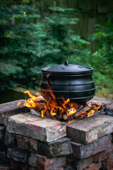 Vertical shot of an old cooking pot placed on the fire in a brick stove outdoors