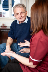 Help the Aged: Home Care. A senior man listening to his visiting healthcare professional. From a series of related images.