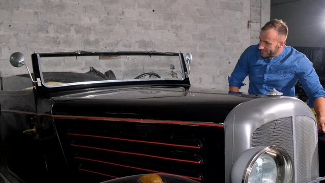 A car enthusiast wipes his retro car in the garage