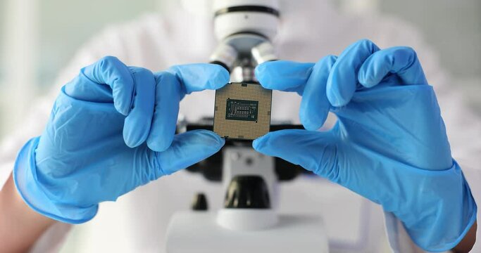 laboratory technician with microscope holds microcircuit