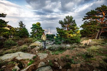 Young man dressed in camouflage on the mountain with his pet.