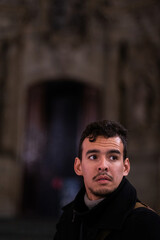 Face portrait of young adult latino male with large space and urban background behind.