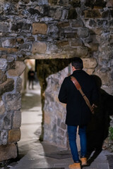 An unrecognizable young Latino with his back to us crossing a door in the wall.