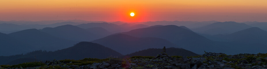 Panorama Silhouettes of Carpathian mountains in a natural blue-red gradient with the sun in the...
