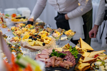 hands of a waiter prepare food for a buffet table in a restaurant