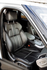 Front view of passenger seat in car, black leather seat upholstery, expensive interior of the...