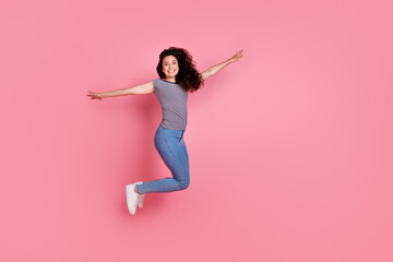 Full length body photo of energetic girlfriend flying air with hands wings travel everywhere isolated over pastel pink color background