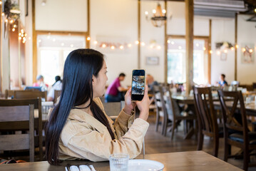 Woman use cellphone to take photo in restaurant