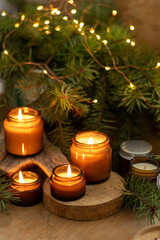 Soy candles burn in glass jars. Comfort at home. Candle in a brown jar. Scent and light. Scented handmade candle. Aroma therapy. Christmas tree and winter mood. Cozy home decor. Festive decoration.