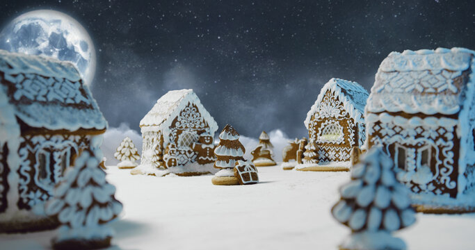 Magic Christmas night scene with gingerbread village. Big moon and moving clouds around