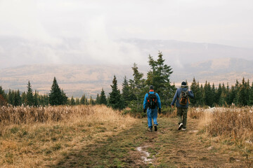 a group of tourists with backpacks is walking through a mountainous area rear view