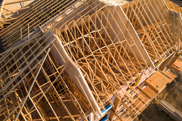 Roofing construction aerial. Wooden roof frame installation of the house. Truss beams structures on new home view from above. Golden hour. House or family home construction and real estate. - obrazy, fototapety, plakaty