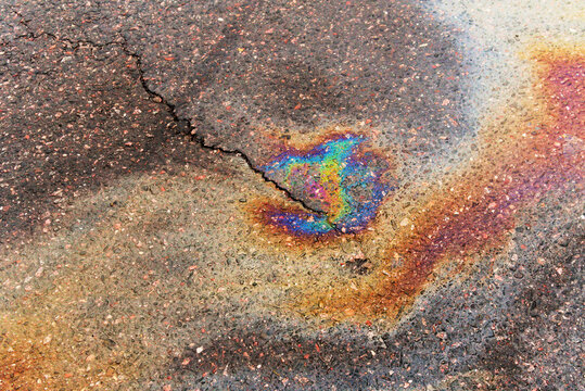 Gasoline pollution, oil, rainbow gasoline leak on asphalt with crack