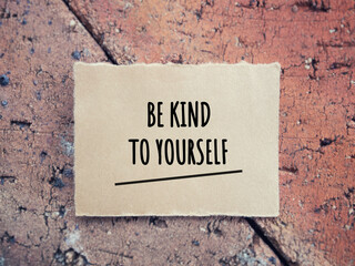 Motivational and inspirational wording. BE KIND TO YOURSELF written on a paper. With blurred style background.