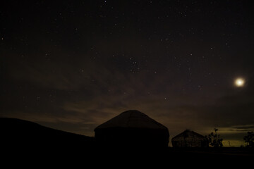 Yurts in the darkness of the night against the backdrop of the starry sky in the desert
