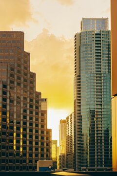 Vertical aerial view of modern glass buildings against bright yellow sunset sky background in Austin