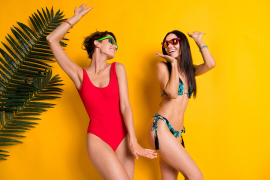 Photo of shiny adorable ladies wear bikini dancing having fun pool party isolated yellow color background