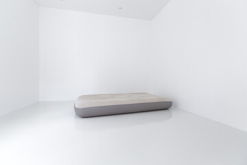 Portable air inflating mattress on white  floor