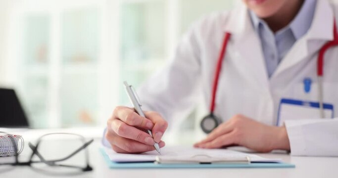 Hands of therapist make notes with pen in medical record