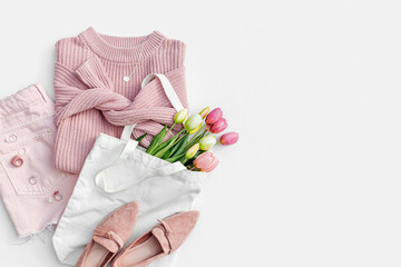 Fashion spring outfit. Pale pink jumper with bouquet of tulips flowers in bag,  jeans and loafers....