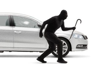 Burglar with balaclava and a crowbar breaking a car window