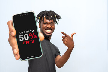 Excited African man holding smartphone advertising discount offer message on the screen. Design...