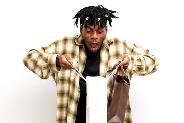 Photo of a Shocked young black African man on dreadlocks with shopping bags isolated on white background. Black Friday sale
