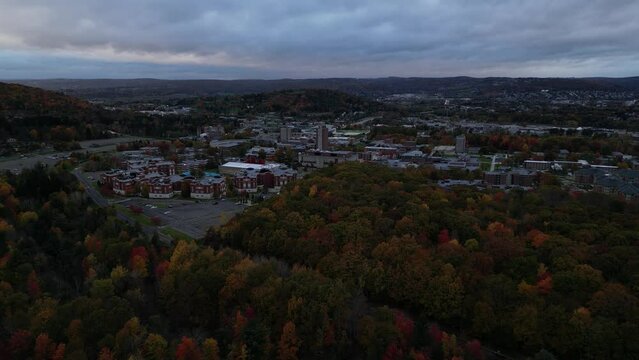 binghamton university campus at dusk (aerial footage, seen from the nature preserve) from above, drone shot panning side to side establishing (college, students, education) new york