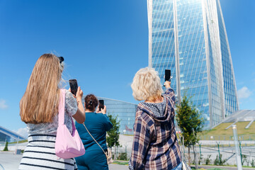 Tourists take pictures on a smartphone of the landmark of St. Petersburg - a high-rise building