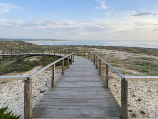 A wood pedestrian walkways, build over a sand dune that is used to give beach access in Furadouro beach, glows at sunset. Ovar, Aveiro, Portugal, Europe