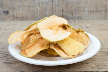 Sliced, dried apples in a plate isolated on wooden background. Homemade organic apple.