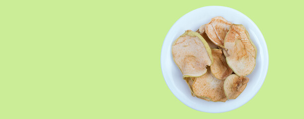 Sliced, dried apples in a plate isolated on green background. Homemade organic apple. Banner