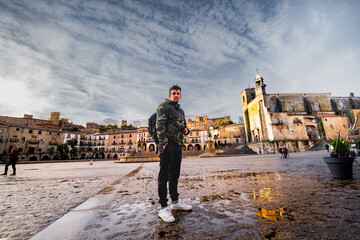 Latin Traveler Explores Tranquil Trujillo Square at Autumn Sunset.