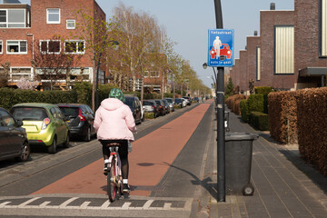 Cycle path through a residential area with a traffic sign with the text; bike path, cars are guests.