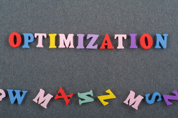 OPTIMIZATION word on black board background composed from colorful abc alphabet block wooden letters, copy space for ad text. Learning english concept.