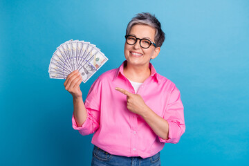 Portrait of toothy beaming person with white grey hair wear stylish blouse indicating at money in...