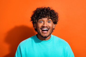 Portrait of astonished cheerful man open mouth unexpected proposition isolated on orange color background