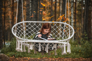 girl with freckles with a book among autumn leaves