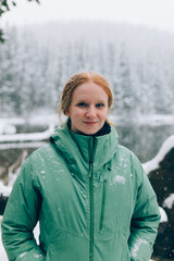 Female Hiker enjoying snowfall beside a lake in the mountains