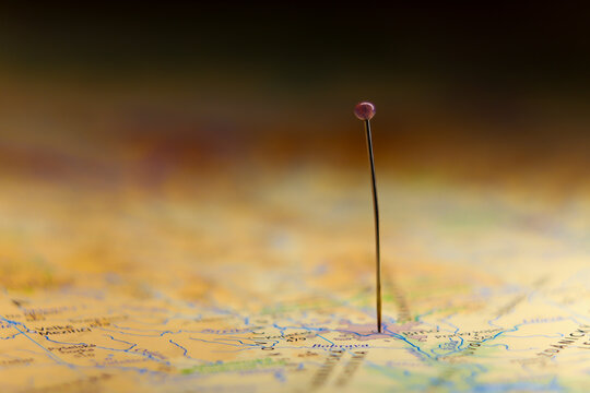 Straight pin in map. Black background. Selective focus.