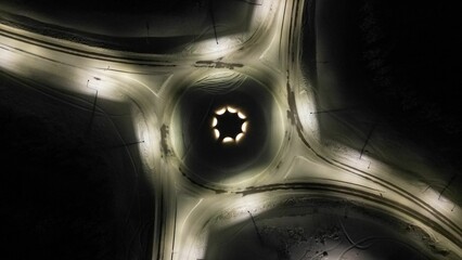 Aerial view of slightly illuminated empty suburban roundabout in winter at night © Wirestock