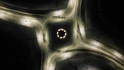 Aerial view of slightly illuminated empty suburban roundabout in winter at night