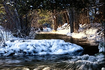 View of a river stream surrounded by snow in winter.